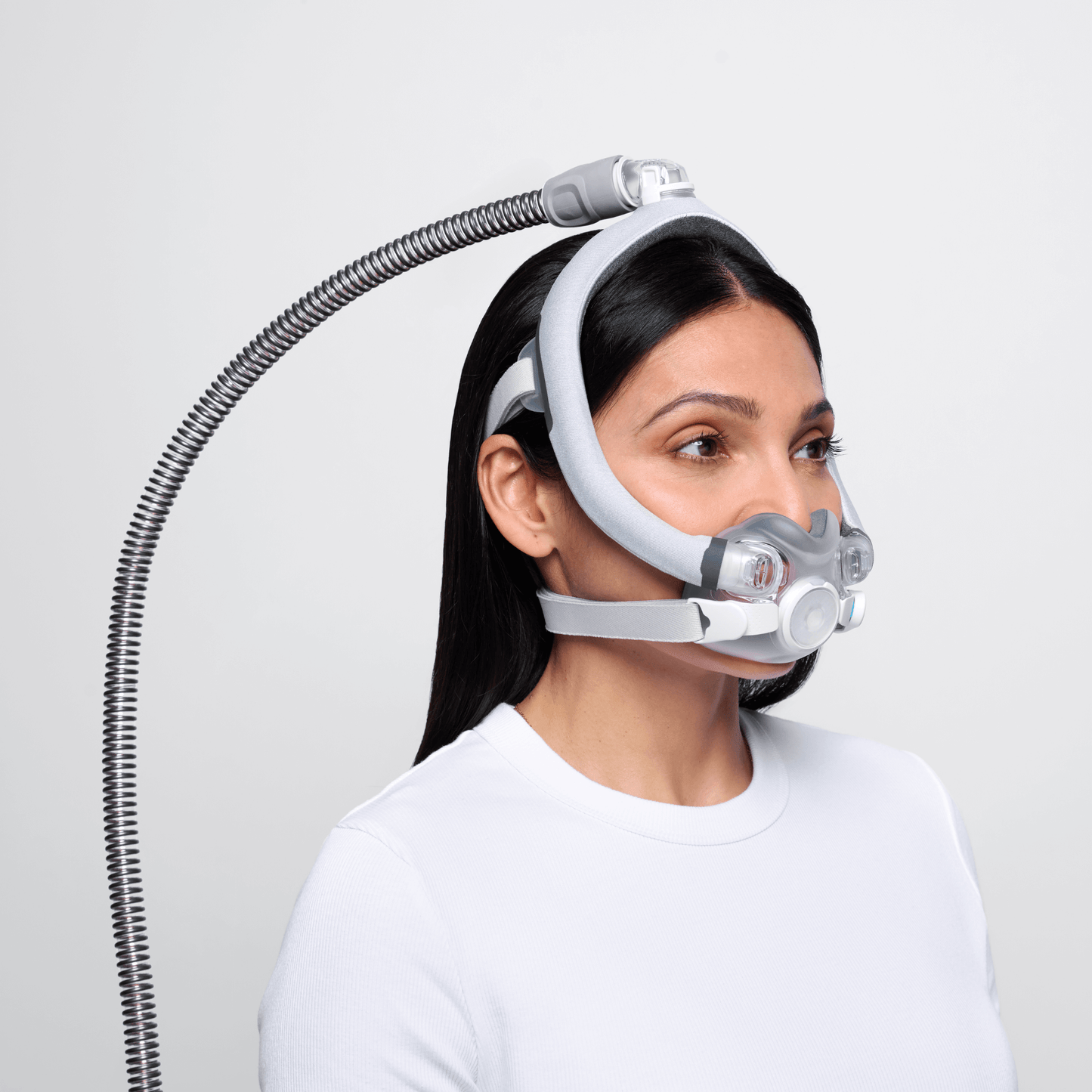 Side profile view of a woman wearing the ResMed AirTouch F30i Comfort CPAP mask, showcasing the soft fabric-wrapped frame and top-of-head tube connection.