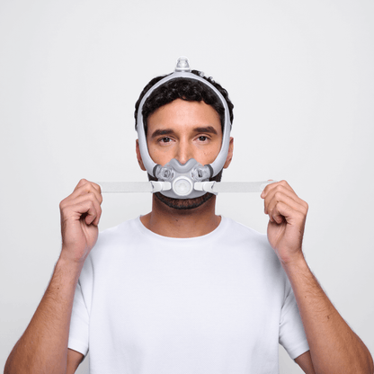 Front view of a man adjusting the ResMed AirTouch F30i Comfort mask, highlighting the fit of the under-the-nose cushion and the flexible fabric frame.