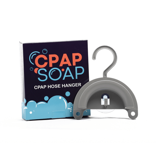 CPAP Soap Hose Hanger with product packaging — gray semi-circular hanger body showing top hook and suction cup base on white background