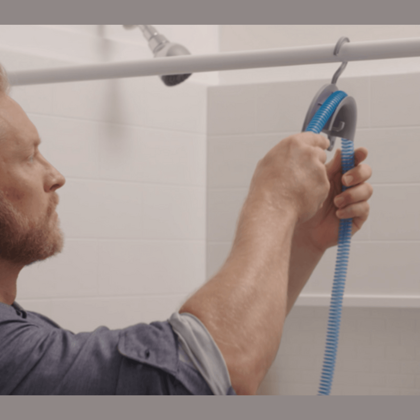 Man draping a CPAP hose over the CPAP Soap Hose Hanger hooked over a shower rod to air-dry after cleaning