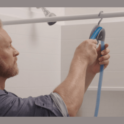 Man draping a CPAP hose over the CPAP Soap Hose Hanger hooked over a shower rod to air-dry after cleaning