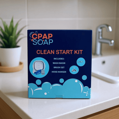 CPAP Soap Clean Start Kit product box on a bathroom countertop listing included items: wash basin, brush set, and hose hanger