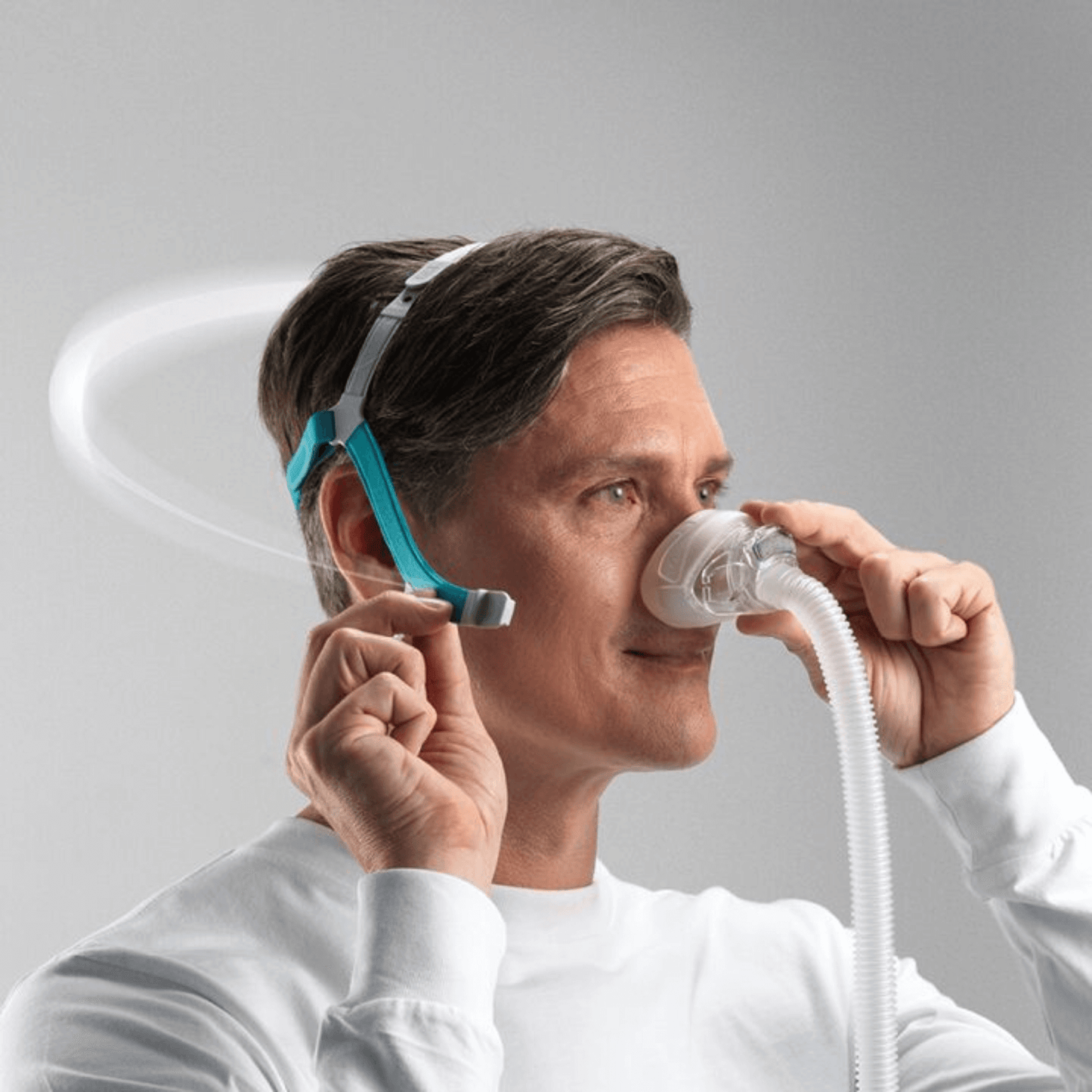 A male user adjusting the Fisher & Paykel Nova Nasal Mask, demonstrating the flexibility and easy adjustment of the SwingFit headgear design.