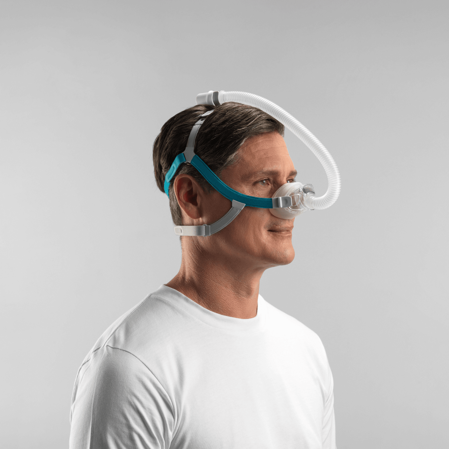 Profile view of a male user sleeping comfortably with the Fisher & Paykel Nova Nasal Mask, demonstrating how the Tube Clip routes the hose over the head to keep it out of the way.