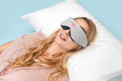 Lady wearing the manta sleep mask while smiling in bed. 